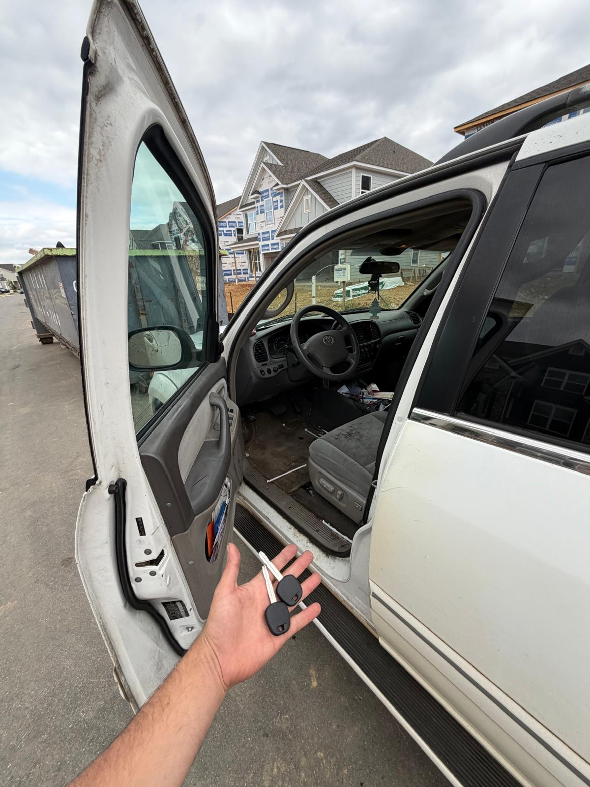 Technician holding new transponder keys next to a white Toyota Land Cruiser SUV in Charlotte, NC NC