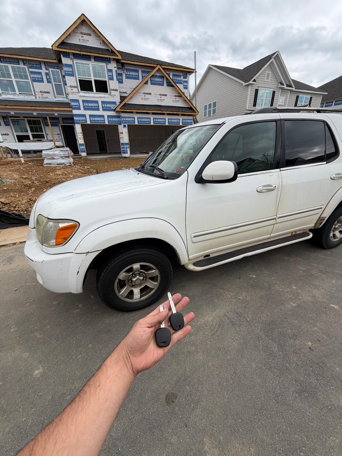 Locksmith showing newly cut transponder keys next to a white Toyota Sequoia SUV in Charlotte, NC NC