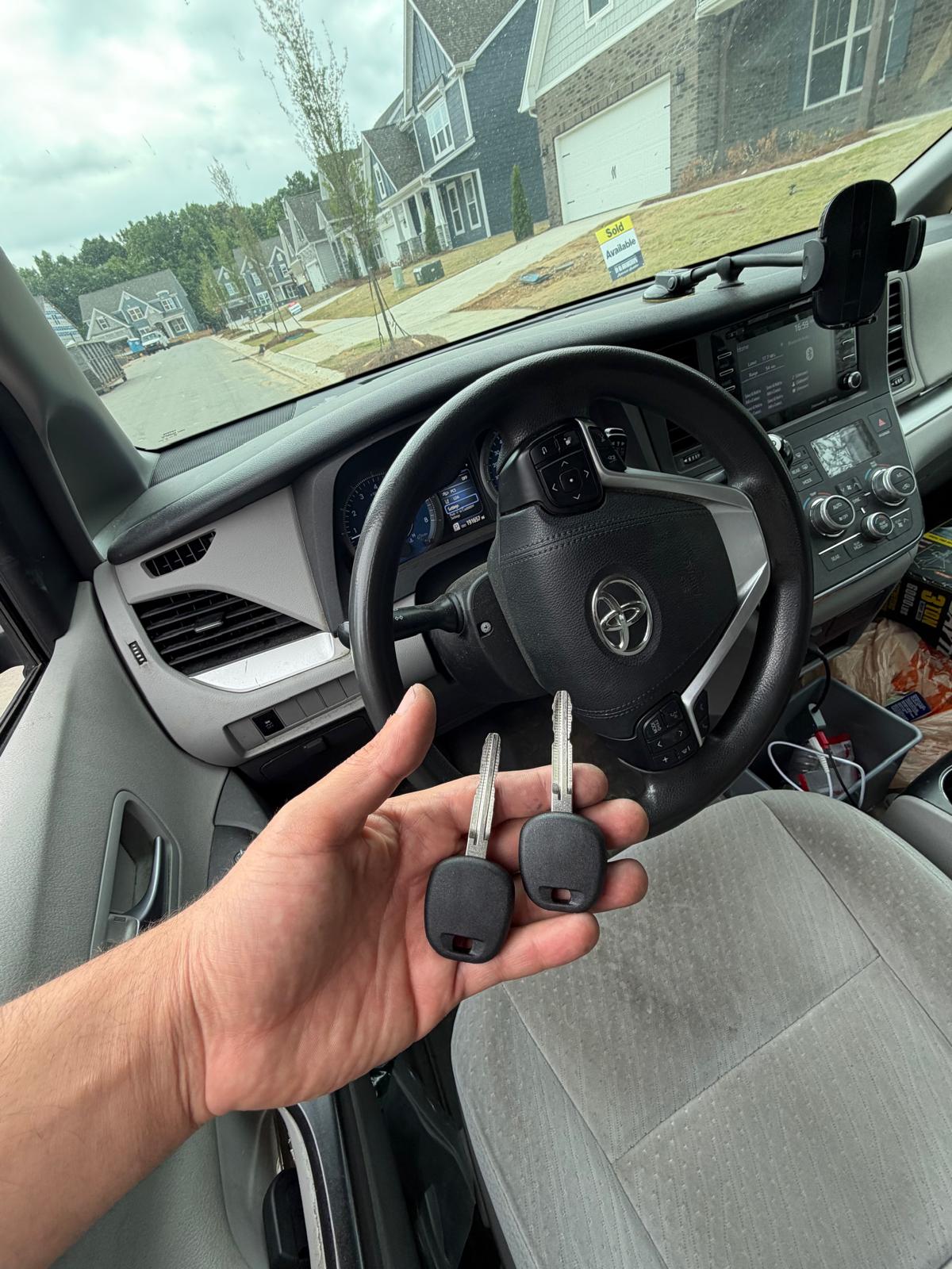 Two cut transponder keys next to a Toyota steering wheel inside a Sienna minivan during a custom Locksmith Services job in Charlotte, NC